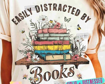May include: Cream-colored t-shirt featuring the text "EASILY DISTRACTED BY BOOKS." The design includes a stack of colorful books on a wooden shelf, adorned with flowers, butterflies, and bees. The words "PNGs" and "SUBLIMATION" are also present.