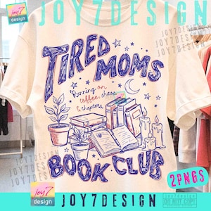 May include: Cream-colored t-shirt with a blue graphic design. The design features the words "Tired Moms Book Club" with illustrations of books, candles, plants, and stars. The text "Running on coffee, chaos & chapters" is also included.