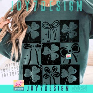 Puede incluir: Una sudadera verde azulado con un dise&ntilde;o de cuadr&iacute;cula con tr&eacute;boles y lazos negros. El texto "JOY7DESIGN" se muestra en la parte superior e inferior. El dise&ntilde;o incluye el texto "joy7 design" en un peque&ntilde;o cuadrado.