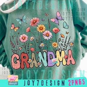 May include: A teal sweatshirt featuring a floral design with butterflies and the word "GRANDMA" in colorful bubble letters. The design includes various flowers in shades of pink, yellow, and white, with butterflies in blue, pink, and orange.