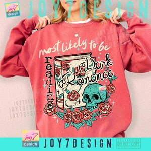 May include: A coral-colored sweatshirt featuring the text "most likely to be reading Dark Romance." The design includes a book, roses, and a teal skull. The sweatshirt has long sleeves and a crew neck.