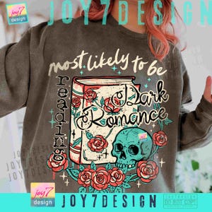 May include: Dark gray sweatshirt with a graphic design featuring a book, roses, and a teal skull. The text reads "most likely to be reading Dark Romance". The design includes the text "joy7 design".