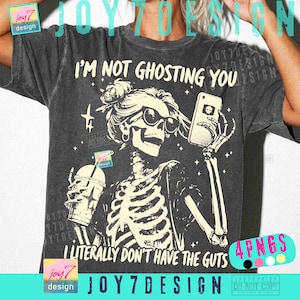 May include: Charcoal grey t-shirt featuring a skeleton illustration wearing sunglasses, holding a phone and a drink. The text on the shirt says "I'M NOT GHOSTING YOU I LITERALLY DON'T HAVE THE GUTS."