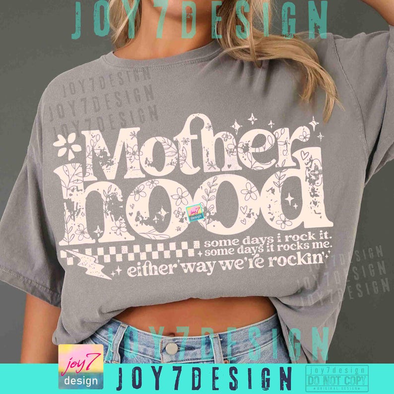 Peut inclure: Un t-shirt gris avec le mot "Motherhood" en grand, dans une police d&eacute;corative orn&eacute;e de motifs floraux et d'&eacute;toiles. La phrase "some days I rock it, some days it rocks me, either way we're rockin'" est imprim&eacute;e en dessous.