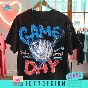 May include: Black t-shirt with a baseball-themed graphic. The design features the words "GAME DAY" in blue and red, along with a baseball, glove, and bat illustration. Additional text includes "Baseball Season", "Batter, Batter, Swing".
