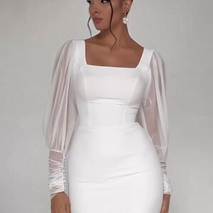 Pode incluir: Um vestido branco de manga comprida com decote quadrado e corpo justo. O vestido tem mangas bufantes transparentes com punhos franzidos.