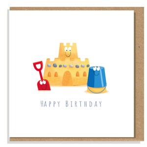 May include: A square greeting card featuring a cartoon illustration of a tan sandcastle with a smiling face, a red plastic shovel, and a blue plastic bucket with a face. The text HAPPY BIRTHDAY is printed in blue below the illustrations.