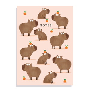 May include: A pink background with the word "NOTES" in black text. There are nine brown capybaras with orange fruit on their heads or near them.