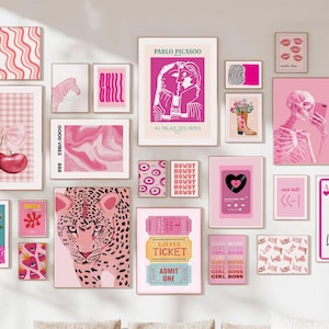 Gallery wall featuring a curated collection of diverse prints and artwork.  The pieces include floral patterns in pink and blue, a queen of hearts playing card, a cat in a window scene, an evil eye, and various abstract designs.  The color palette is vibrant, with pinks, blues, and greens dominating. The prints are framed in light wood and arranged in a visually appealing, eclectic style.  The overall theme is modern and playful.