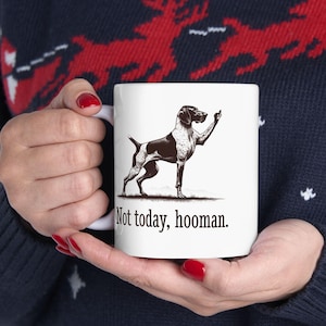 May include: White ceramic mug with a black and white illustration of a dog giving the middle finger. The text "Not today, hooman." is printed below the dog.