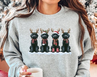 May include: A grey sweatshirt with a Christmas-themed design featuring four black dogs wearing reindeer antlers and Santa hats. The dogs are sitting in a row on a snowy background. The sweatshirt is labelled "Sport Grey".