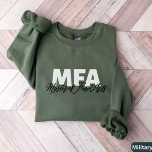 May include: A military green sweatshirt with the text "MEA Master of Fine Arts" printed in white and black.