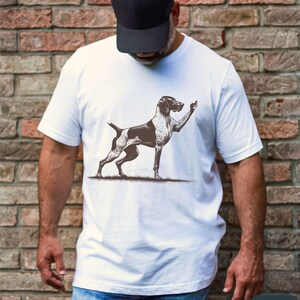 May include: White t-shirt with a black and white illustration of a dog giving a thumbs up.