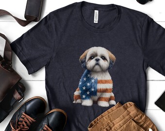 May include: A heather navy blue t-shirt featuring a white Shih Tzu dog wearing a red, white and blue American flag bandana. The dog is sitting and looking at the camera. The t-shirt is on a white wooden surface with brown leather accessories and brown trousers.