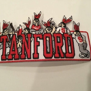 Könnte beinhalten: Roter und weißer gestickter Aufnäher mit dem Wort "STANFORD" in roten Buchstaben und einer Gruppe von Cartoon-Figuren, die rote und weiße Kleidung und Hüte tragen.