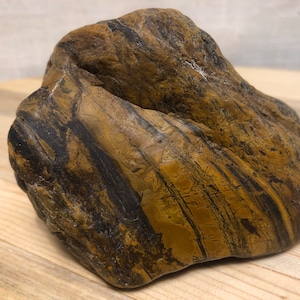 May include: A large, smooth, brown and black striped rock with a unique, organic shape.