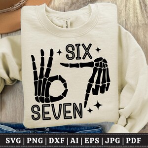 May include: Cream-colored sweatshirt with a black skeleton hand design indicating the numbers six and seven. The word "SIX" is above the hand gesture, and "SEVEN" is below. The design includes star accents.