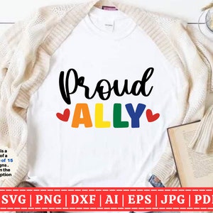 Könnte beinhalten: Ein weißes T-Shirt mit dem Text "Proud Ally" in schwarzer Schrift. Das Wort "Ally" ist in Regenbogenfarben mit einem roten Herzen auf jeder Seite.