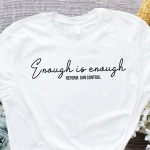 May include: White t-shirt with the text "Enough is enough. Reform. Gun Control." printed in black.
