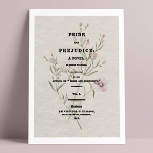 以下が含まれることがあります： 「Pride and Prejudice」のタイトルと花の装飾が施された額入りのプリント。テキストには「A Novel」と「Vol. I」、著者と出版社の詳細が含まれています。プリントはヴィンテージ感のあるデザインです。