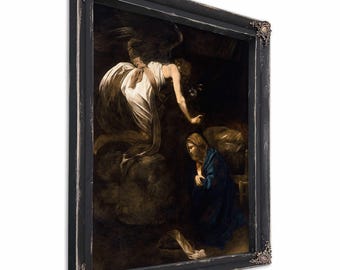 May include: A framed sepia-toned painting depicting a religious scene. An angel in a white gown descends towards a woman in a blue robe. The black frame has ornate corner details and a distressed finish, adding a vintage aesthetic.