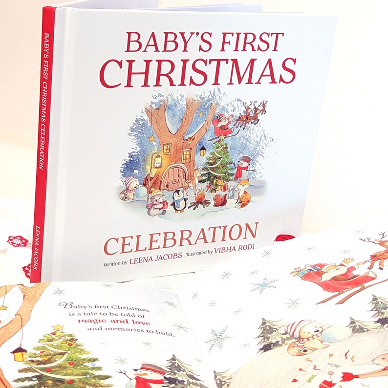 May include: A hardcover book titled "Baby's First Christmas Celebration" with a festive illustration of Santa, reindeer, and woodland creatures. The cover features a red spine and the author's name, Leena Jacobs.