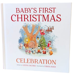 May include: A hardcover book titled "BABY'S FIRST CHRISTMAS CELEBRATION" with a festive illustration. The cover features a winter scene with Santa in a sleigh, a decorated Christmas tree, and woodland creatures. The author is Leena Jacobs, and the illustrator is Vibha Rodi.