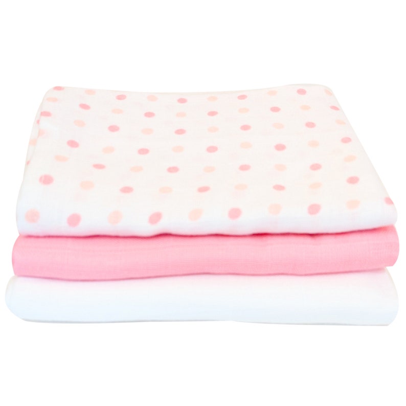 May include: A stack of three baby blankets. The top blanket is white with pink polka dots. The middle blanket is solid pink, and the bottom blanket is solid white. The blankets are folded neatly.