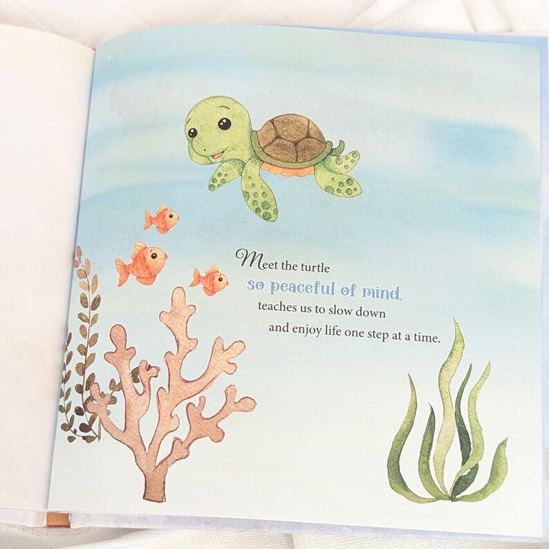 May include: An illustrated page from a children's book features a smiling green turtle swimming above orange fish and coral. Text reads "Meet the turtle, so peaceful of mind, teaches us to slow down and enjoy life one step at a time."