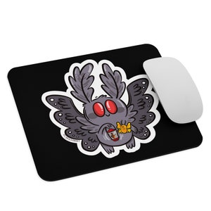 May include: A black mousepad with a white outline of a cartoon moth holding a lantern. The moth has large red eyes and is flying. The moth is surrounded by a white outline.
