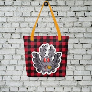 May include: A red and black checkered tote bag with a cartoon illustration of a gray moth holding a cup of coffee. The moth has large red eyes and is surrounded by a yellow flower.