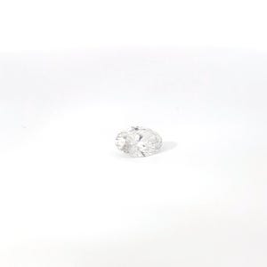 May include: A clear, oval-cut diamond with multiple facets, reflecting light. The gemstone is set against a white background, showcasing its brilliance and clarity. This diamond is a symbol of luxury and elegance.