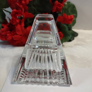 May include: A clear glass pyramid-shaped dish with a square base. The dish has a textured, ribbed design.