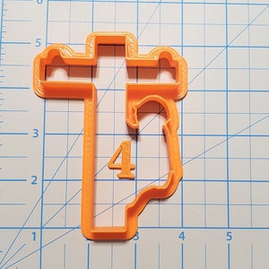 May include: Orange plastic cookie cutter shaped like a cross with the number 4 inside.