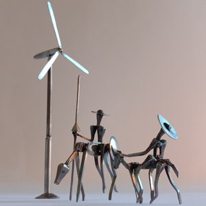 Puede incluir: Una escultura de metal de tres figuras, cada una con un sombrero y montando un caballo. La escultura está hecha de materiales reciclados y es una obra de arte única.