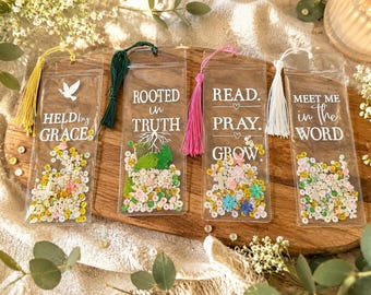 May include: Four clear rectangular bookmarks with tassels. The first says HELD by GRACE with a dove. The second says ROOTED in TRUTH with tree roots. The third says READ. PRAY. GROW. The fourth says MEET ME in the WORD. Each contains colorful sequins.