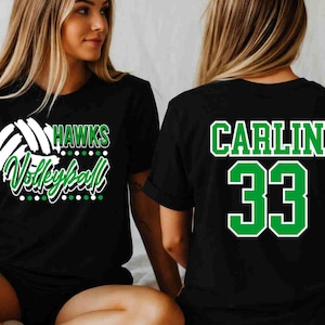May include: A black short-sleeved t-shirt featuring a white and green graphic on the front that reads HAWKS Volleyball with a volleyball icon. The back of the shirt displays the name CARLIN in green with a white outline above the number 33.