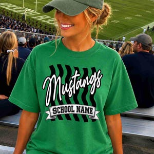 May include: A green short-sleeve t-shirt featuring a graphic design with black vertical wavy lines, the word Mustangs in white script, and a white banner containing the text SCHOOL NAME in black capital letters.