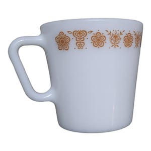 Puede incluir: Taza de cerámica blanca con un diseño floral marrón alrededor del borde.