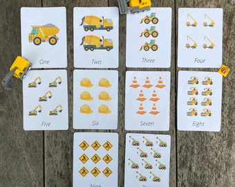 May include: Ten flashcards with different construction vehicles and numbers one through ten. Each card has a white background with black text and colorful illustrations of construction vehicles.