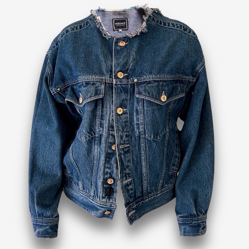 May include: A vintage blue denim jacket with a frayed collar and gold buttons. The jacket has two front pockets and a label that reads "VERSACE".