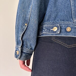 May include: A blue denim jacket with a button closure and a single pocket on the left side. The jacket has a light wash and is made of a soft, comfortable fabric.