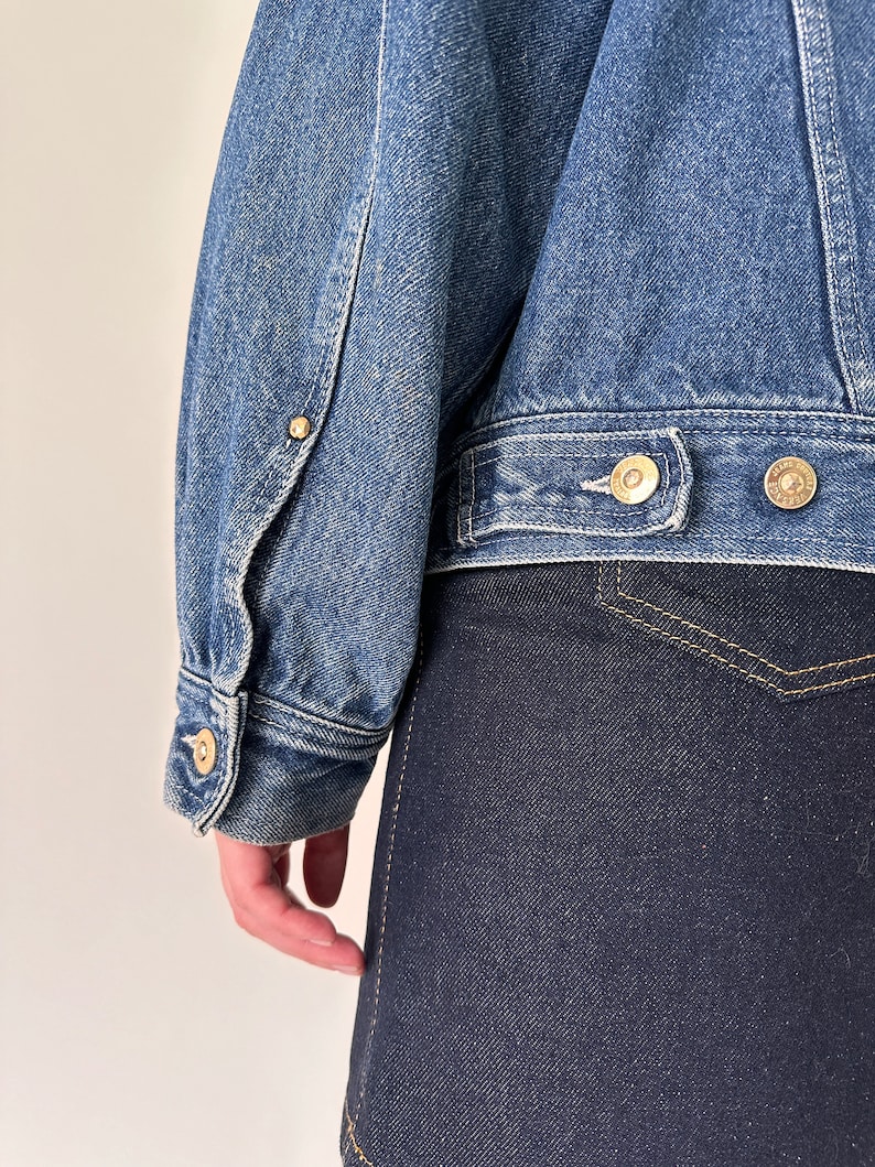 May include: A blue denim jacket with a button closure and a single pocket on the left side. The jacket has a light wash and is made of a soft, comfortable fabric.