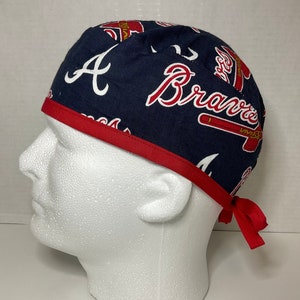 May include: A blue and red baseball cap with the Atlanta Braves logo and the letter "A" printed on it. The cap has a red trim and ties.