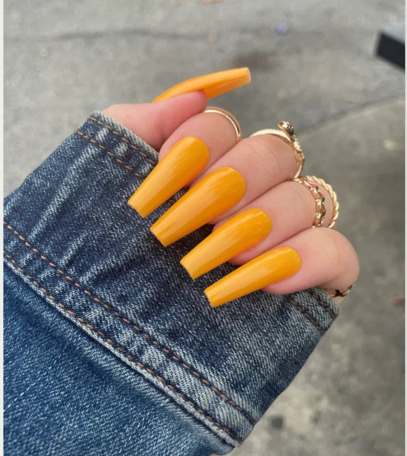 May include: Long, yellow, coffin-shaped acrylic nails