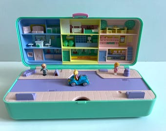 May include: A vintage teal and pink miniature playset, open to reveal a multi-level town scene. The playset includes tiny figures, a blue car, and detailed interior scenes like a post office and chemist.