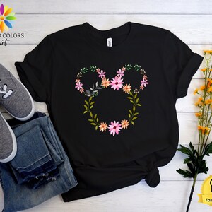 May include: Black t-shirt with a floral design in the shape of Mickey Mouse ears. The flowers are pink, orange, and green.