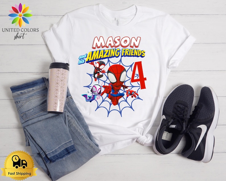 Pode incluir: Uma t-shirt branca de manga curta com um gr&aacute;fico do Homem-Aranha e amigos sobre um fundo de teia de aranha azul. O texto diz MASON and his AMAZING FRIENDS com um n&uacute;mero 4 vermelho grande. A t-shirt &eacute; exibida com cal&ccedil;as de ganga azuis e t&eacute;nis pretos.