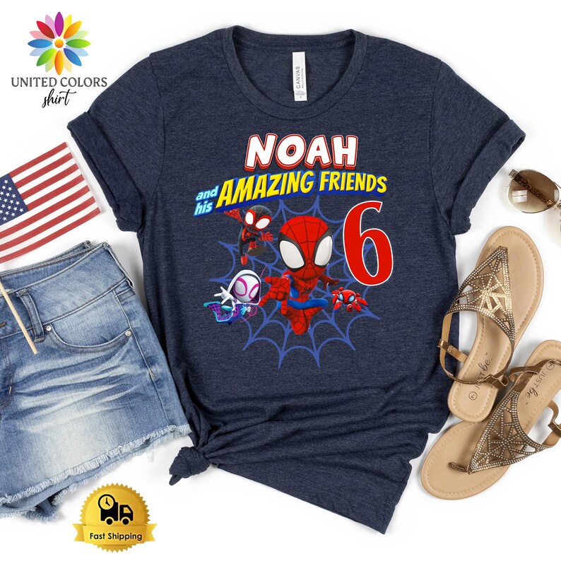 Pode incluir: Uma t-shirt de manga curta azul-marinho escuro com uma impress&atilde;o gr&aacute;fica com o texto NOAH and his AMAZING FRIENDS e um grande n&uacute;mero 6 vermelho. O design inclui personagens de desenhos animados sobre um fundo de teia de aranha.
