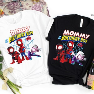 以下が含まれることがあります： スパイダーマンのデザインが施された白と黒のTシャツ2枚。白いシャツには「DADDY of the BIRTHDAY BOY」、黒いシャツには「MOMMY of the BIRTHDAY BOY」と書かれています。どちらのシャツにもスパイダーマンのグラフィックが描かれています。